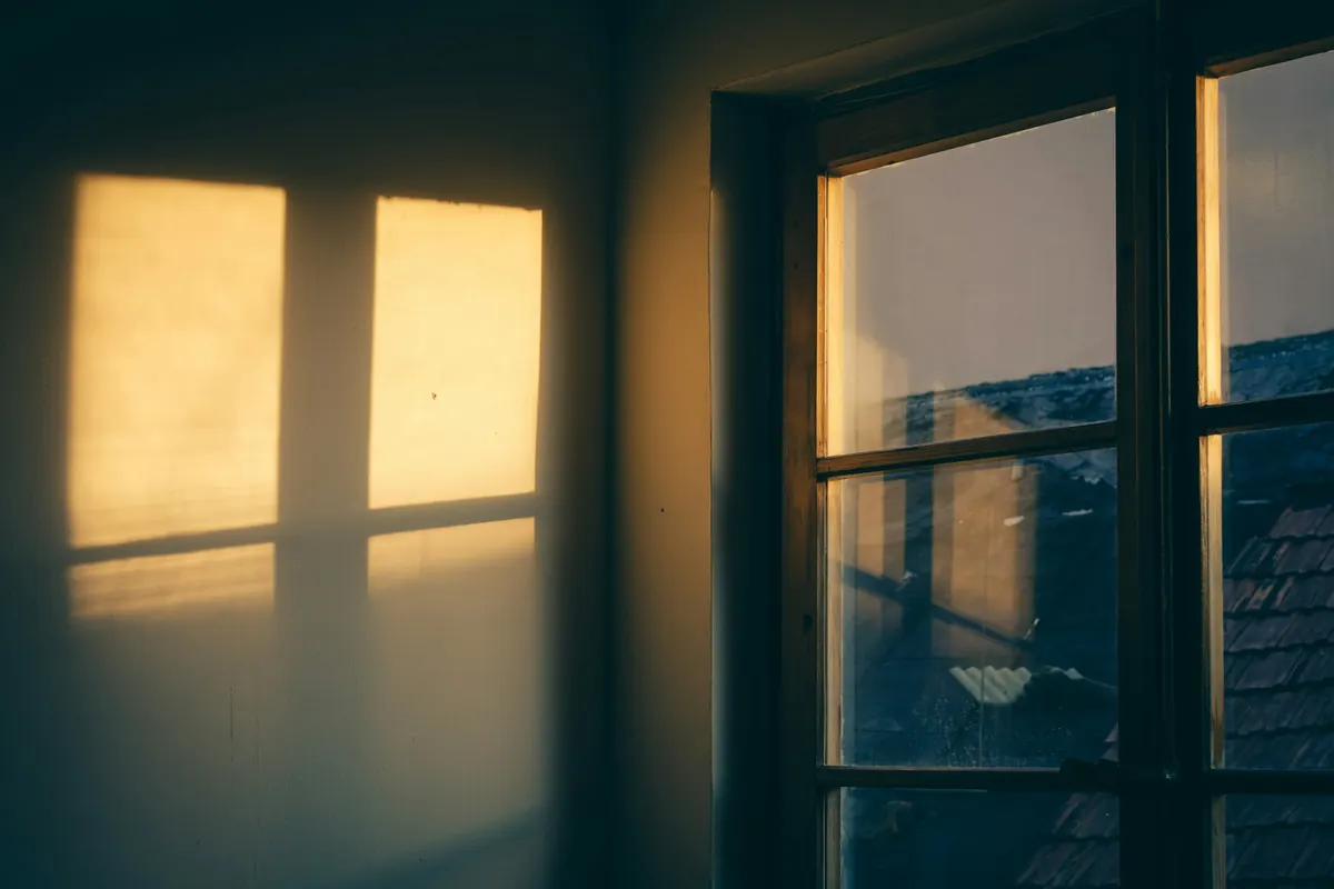 Warm late-day sun falling through a window onto a dim wall